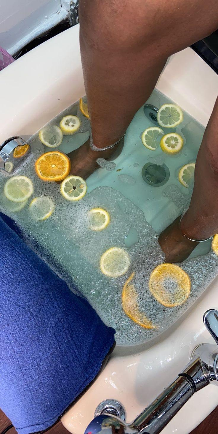 Feet soaking in pale blue water with citrus slices.